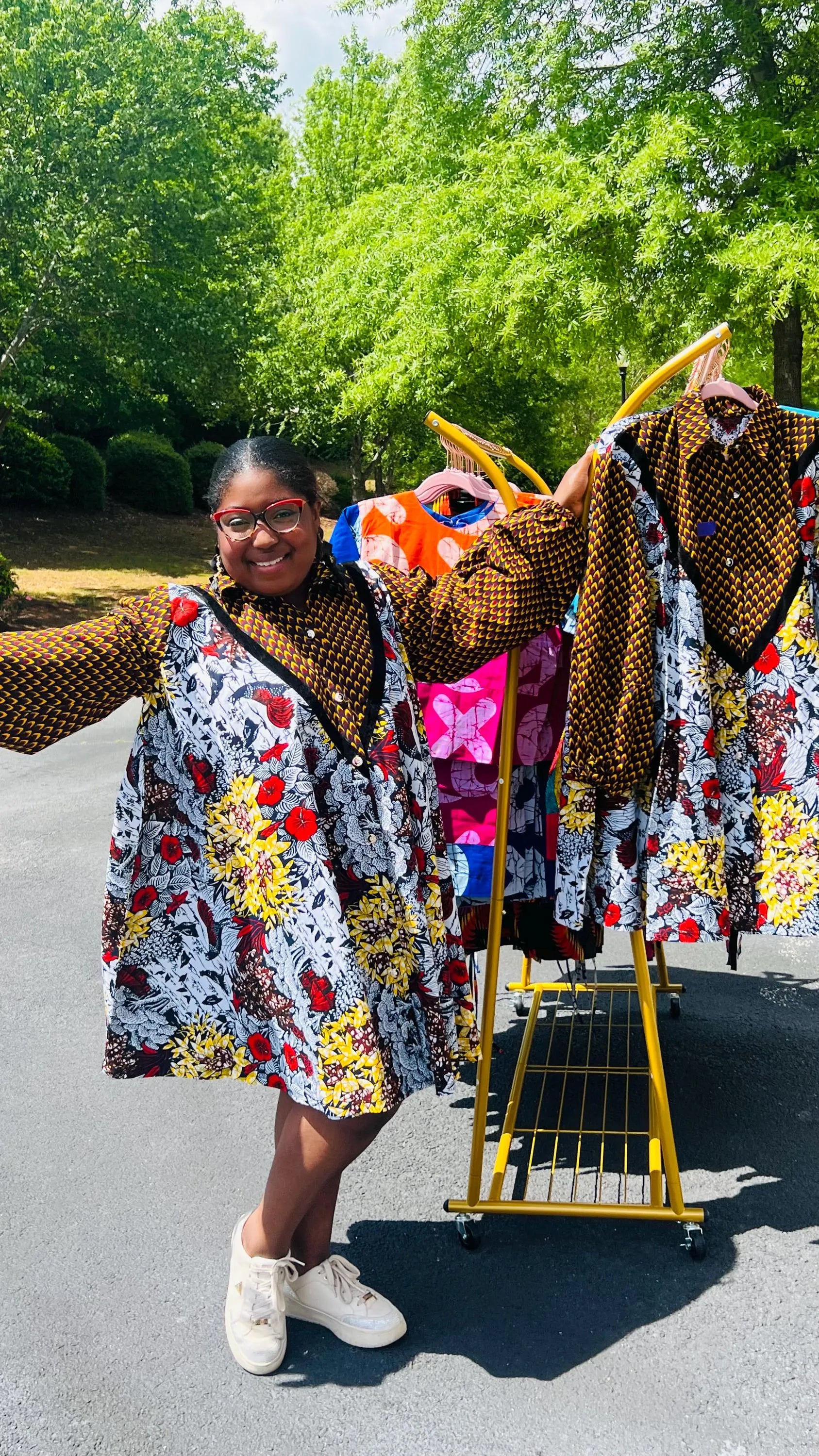 Woman wearing a vibrant Ankara A-line dress with puff sleeves, velvet button-up front, and knee-length hem, standing outdoors.