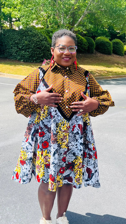 Woman wearing a vibrant Ankara A-line dress with puff sleeves, velvet button-up front, and knee-length hem, standing outdoors.